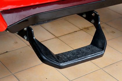 A black step on the side of a red car