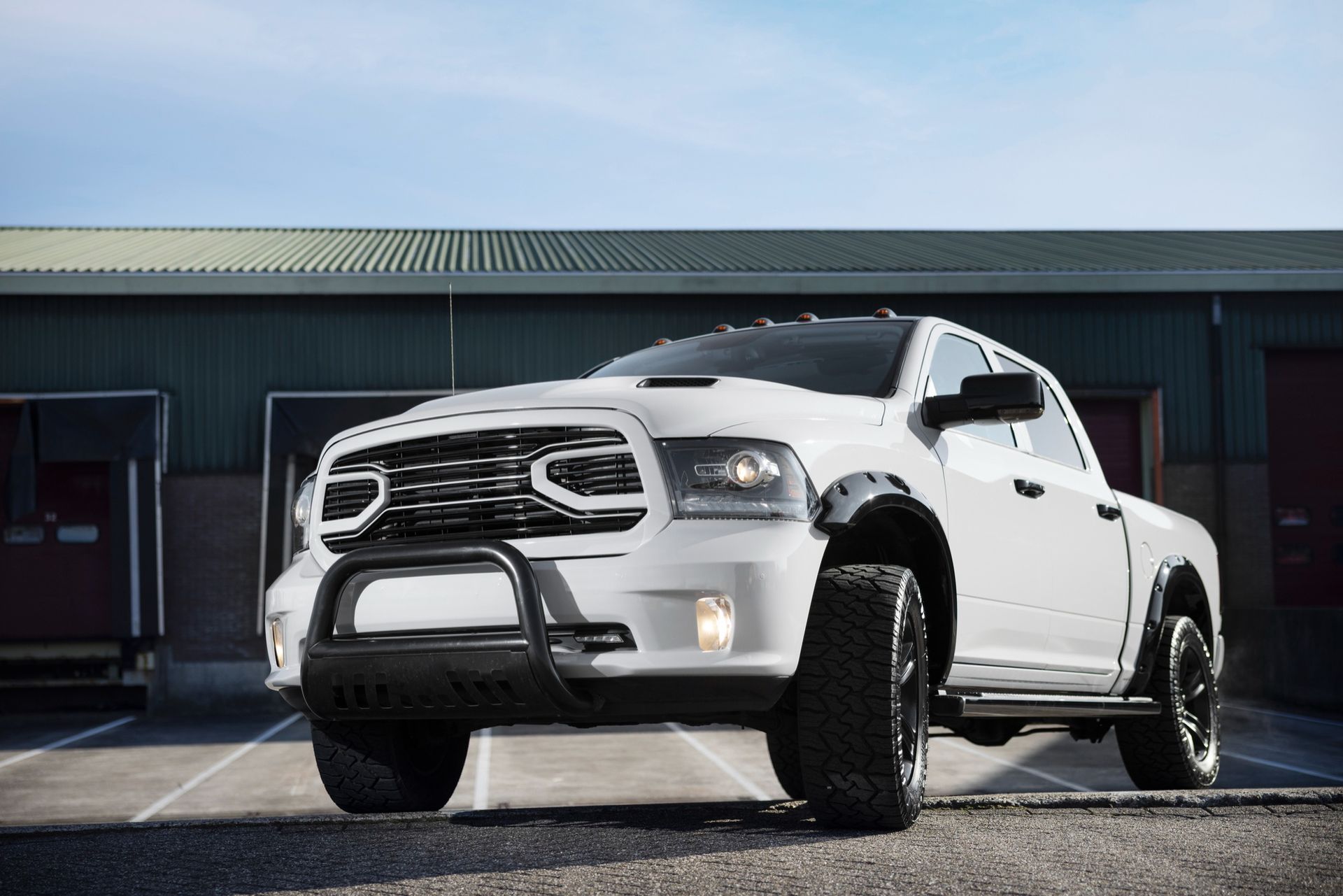 A white dodge ram truck is parked in a parking lot in front of a building.