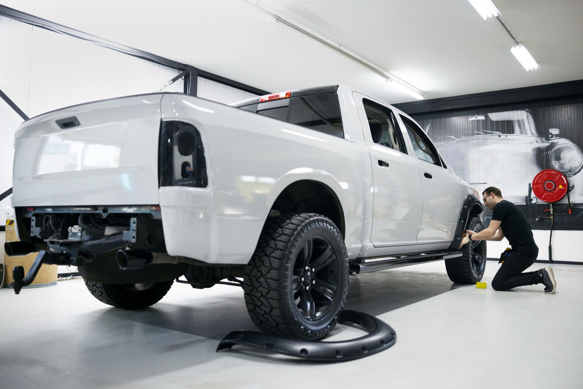 A worker is next to a white truck in a garage.