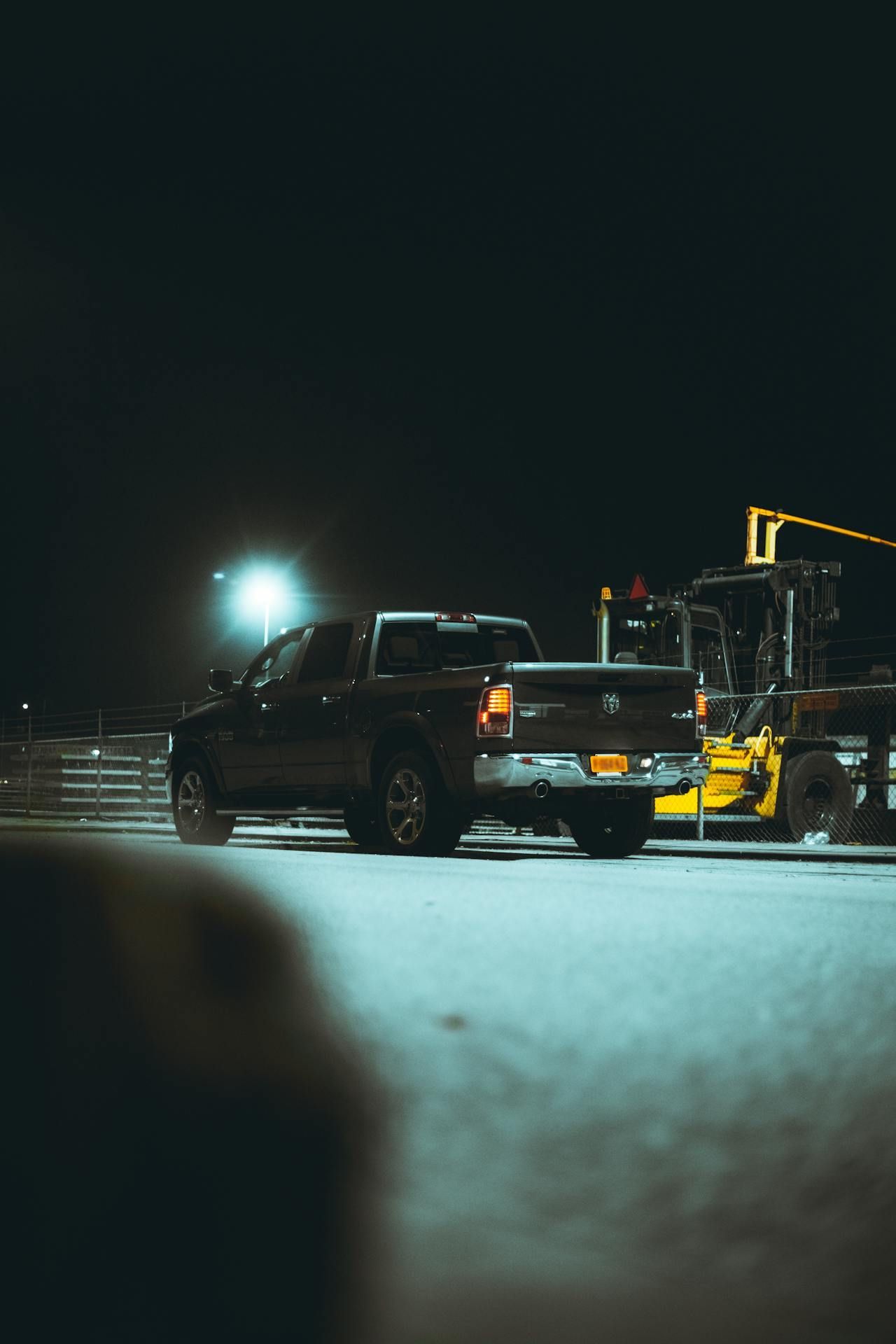 A black truck is parked next to a forklift.