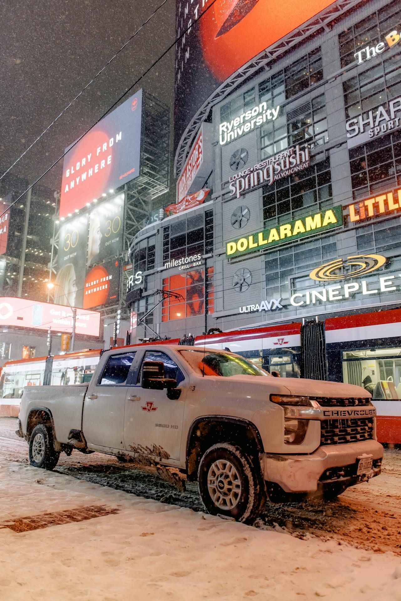 A white truck is parked in the snow in front of a building.