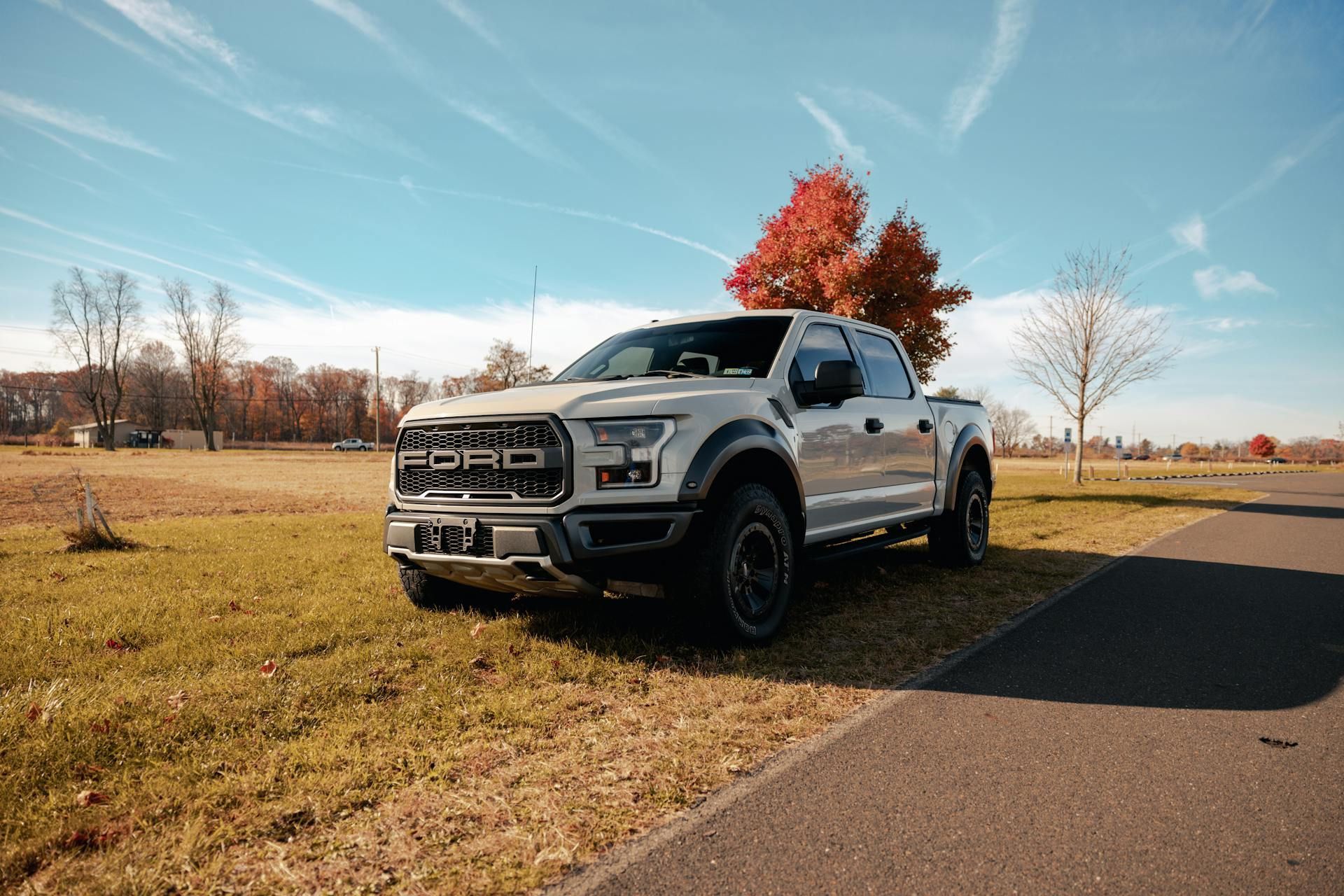 A white ford raptor truck is parked on the side of the road.