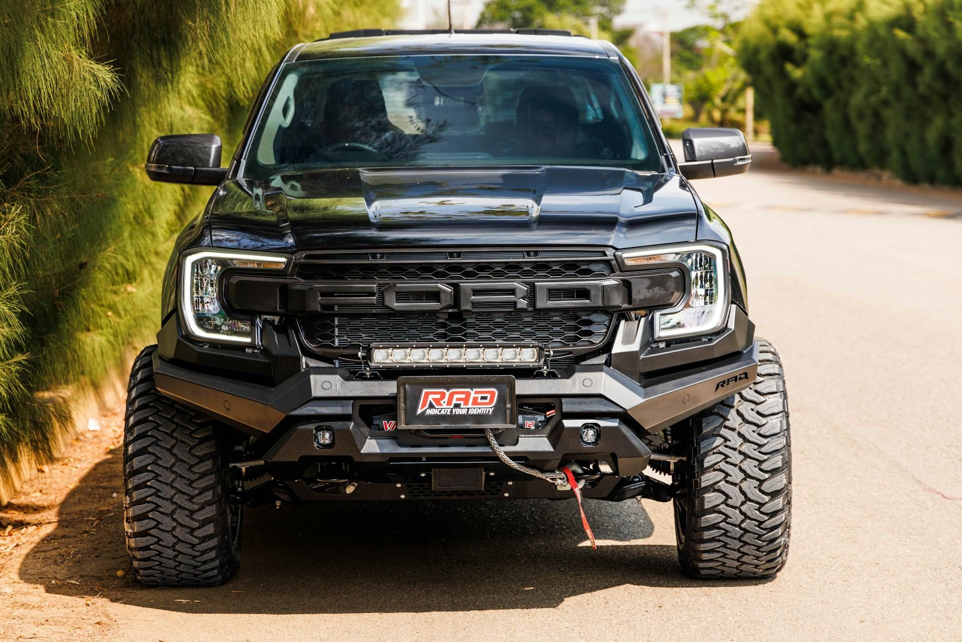 A black ford raptor is parked on the side of a road.