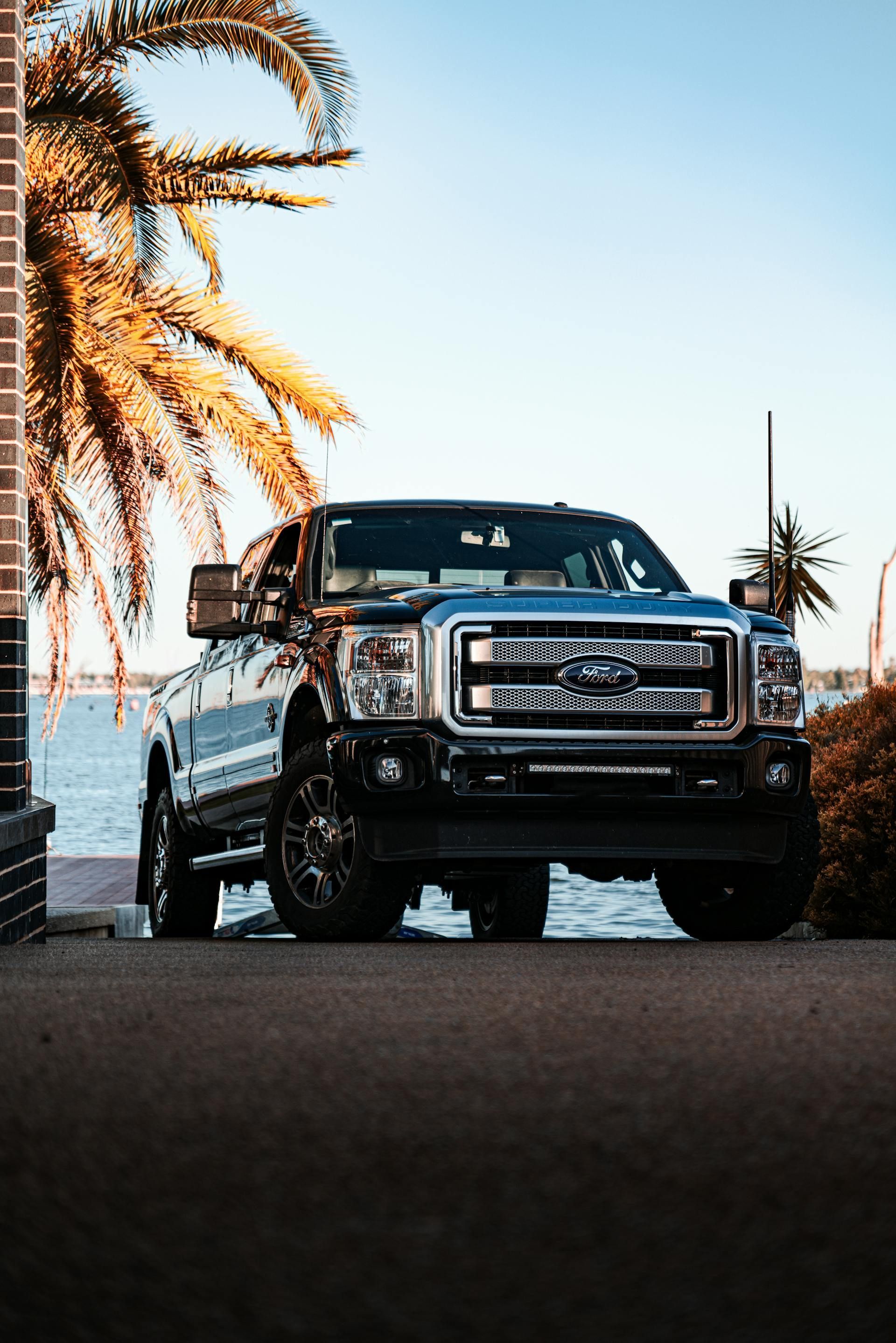 A truck is parked in front of a building next to a body of water.
