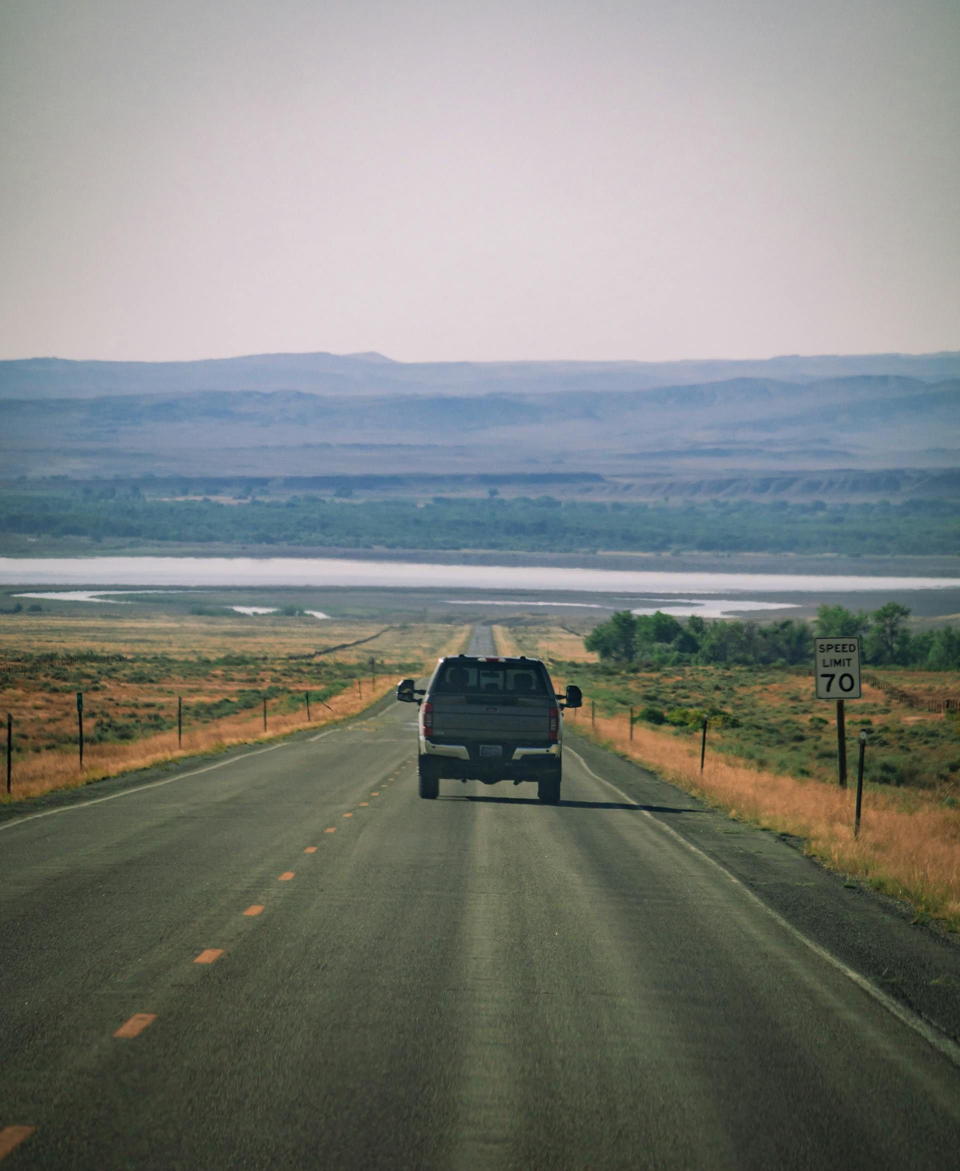 A truck is driving down a road in the desert.