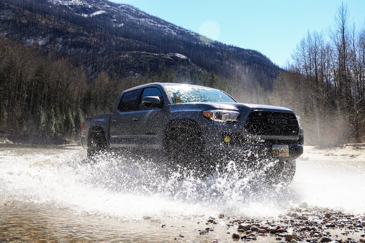 A truck is driving through a river in the mountains.