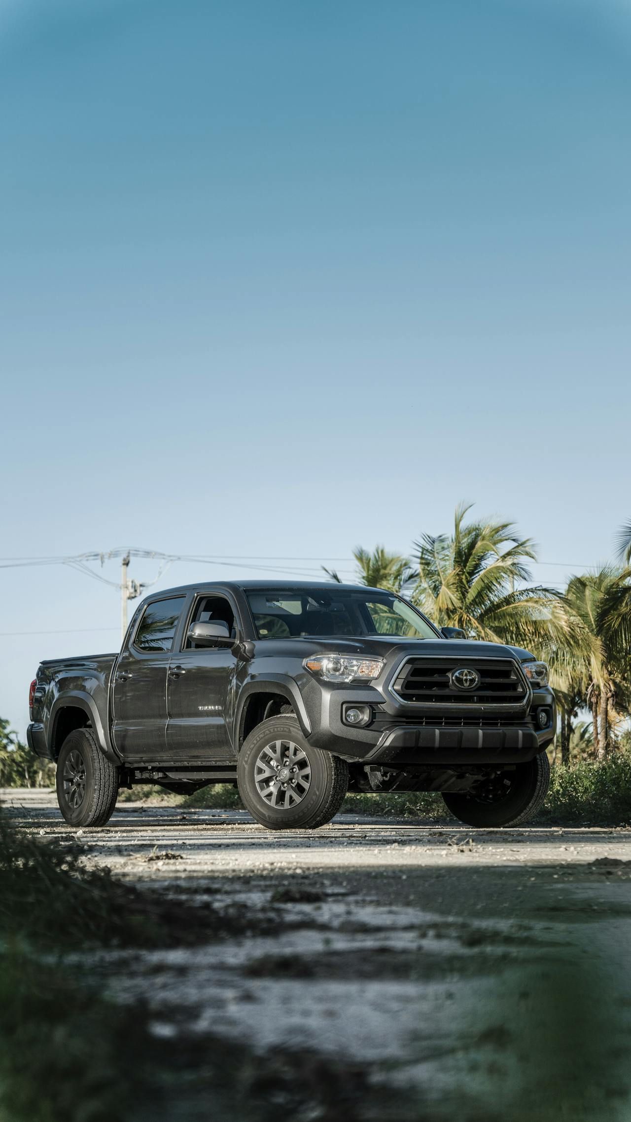 A black toyota tacoma truck is parked on a dirt road.