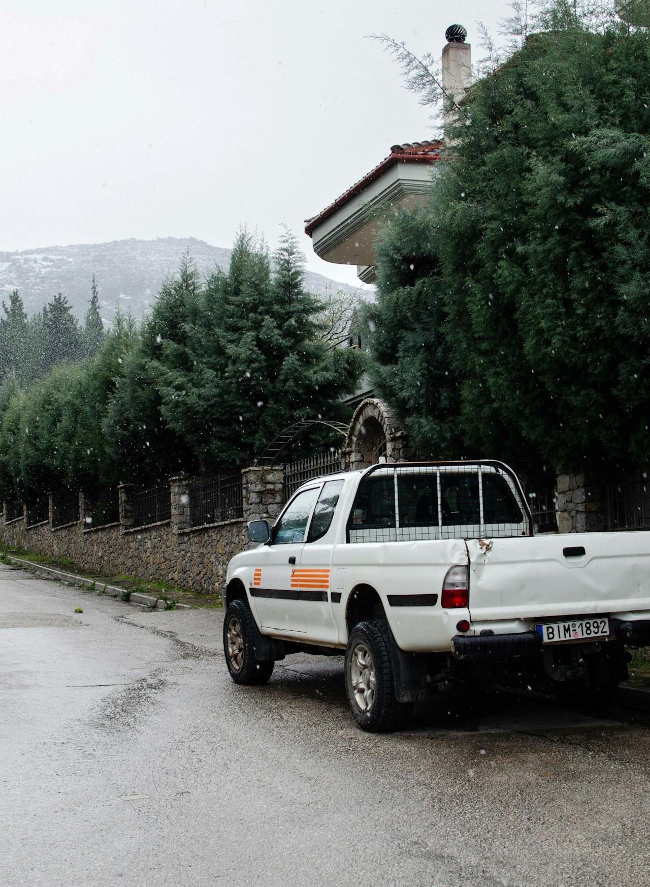 A white truck is parked on the side of the road in front of a house.
