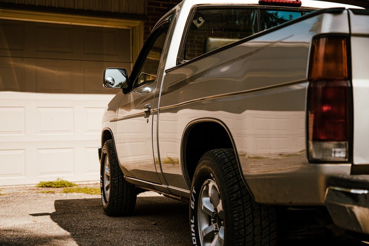 A silver truck is parked in front of a garage door.