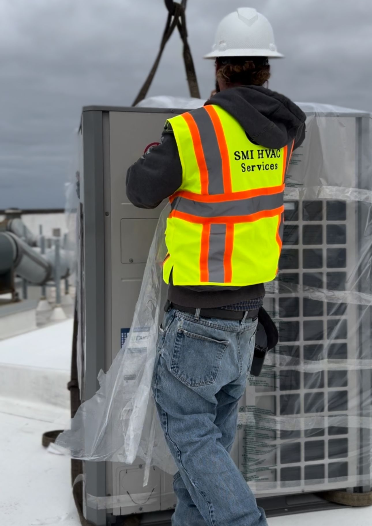 HVAC technician in cap, repairs an outdoor air conditioner, using tools.
