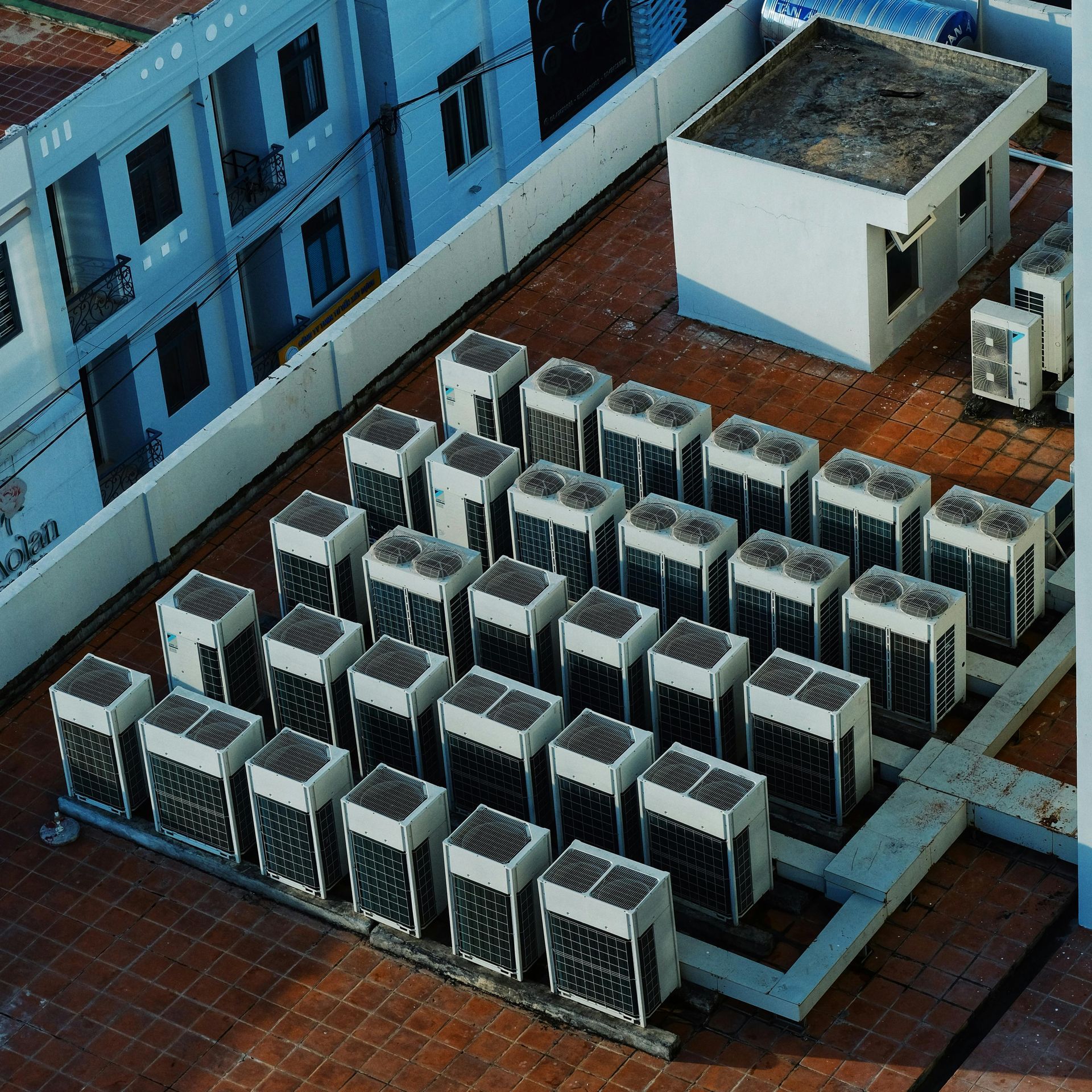 Rooftop HVAC units and a small utility structure beside a blue building.