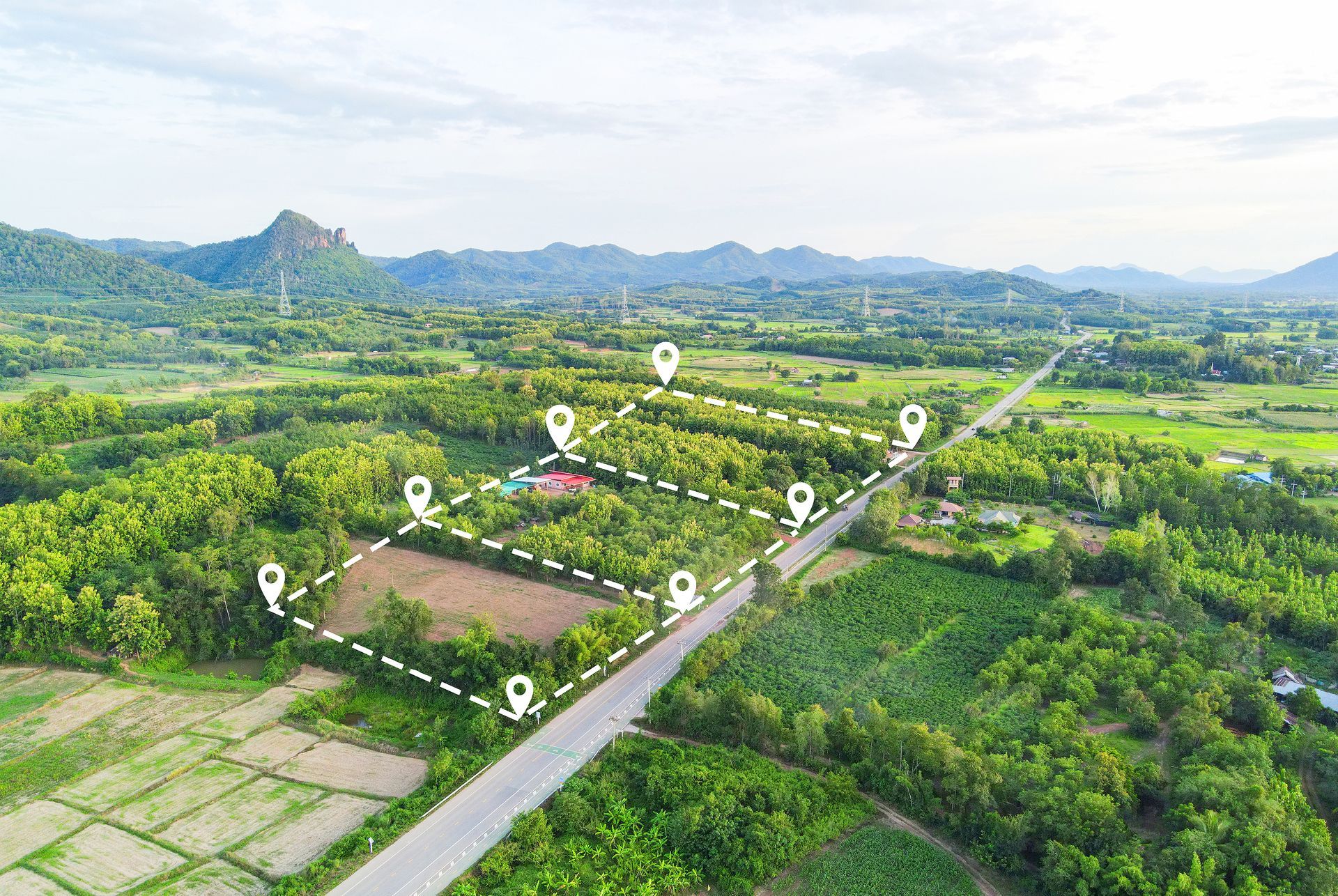 Aerial view of a green rural landscape with fields, a road, and several location markers.