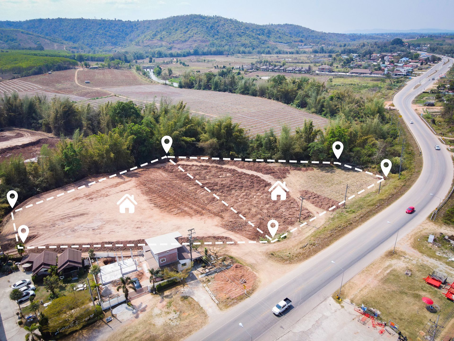 Aerial view of a rural roadside lot with mapped boundary markers, trees, fields, and a winding highway.