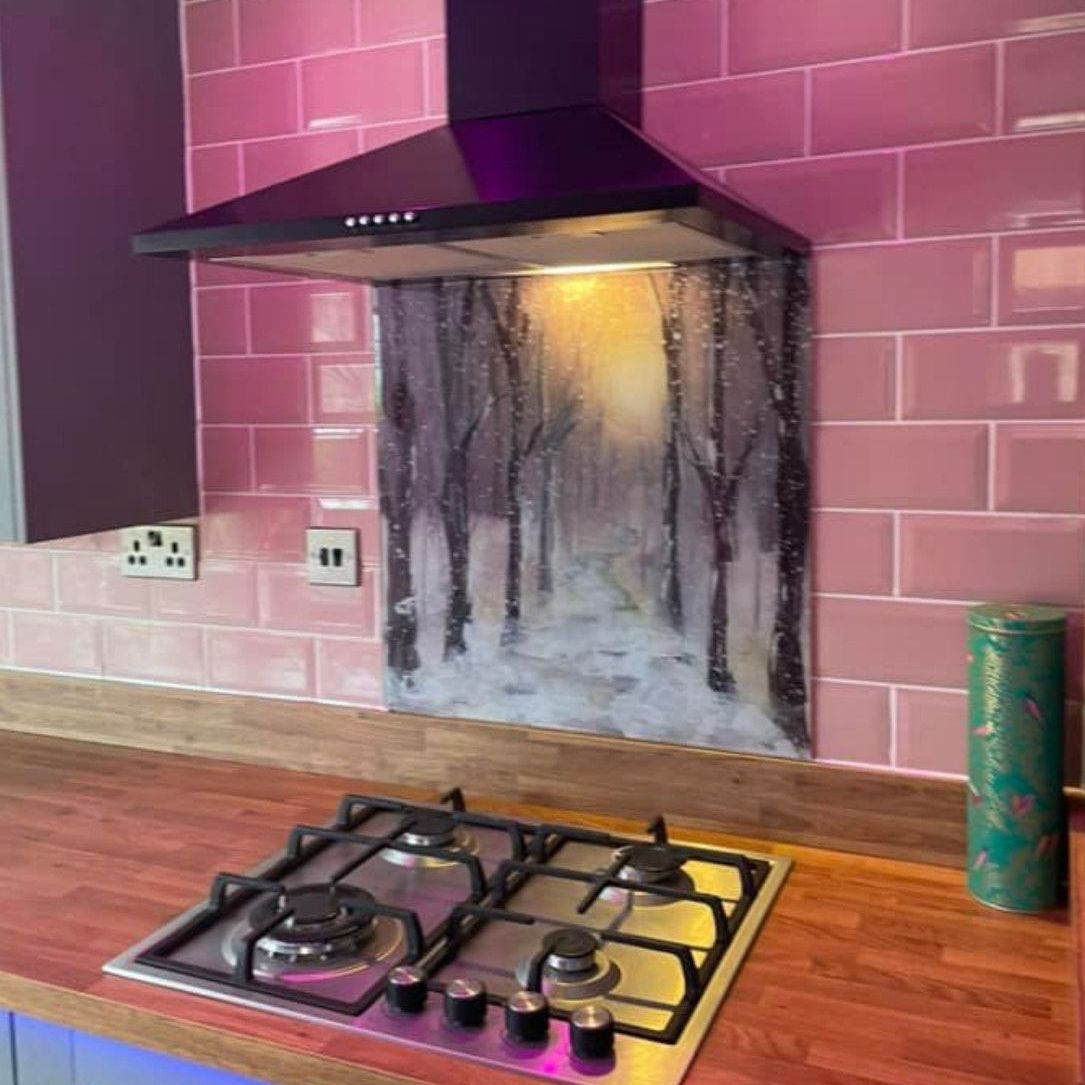 Pink kitchen backsplash with a black range hood, gas stove, and smoke stains on the wall behind it