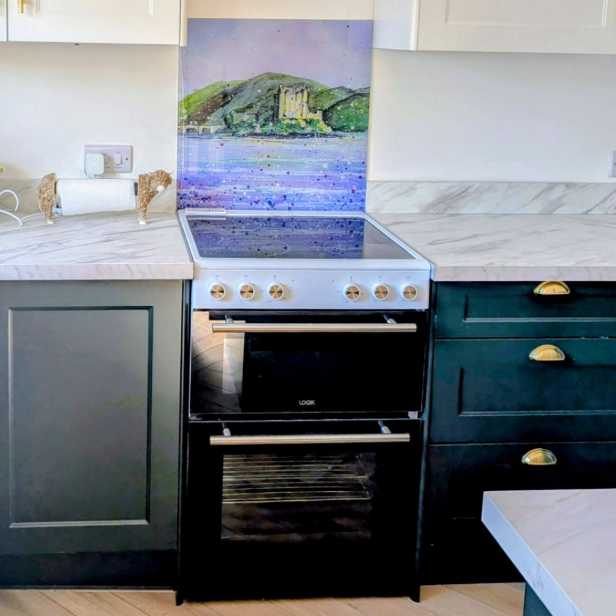 Modern kitchen with dark cabinets, white countertops, a black oven, and a colorful backsplash panel