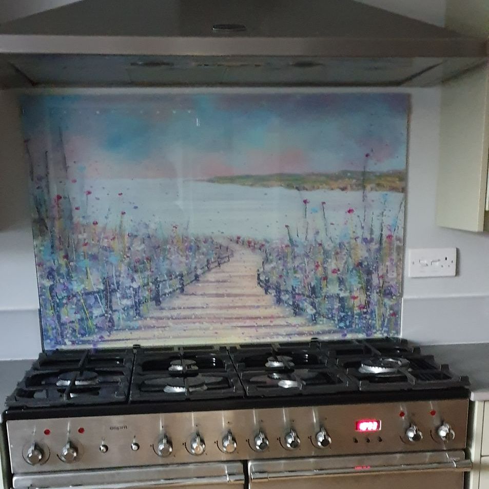 Kitchen stove with black grates and a colorful coastal painting backsplash above it