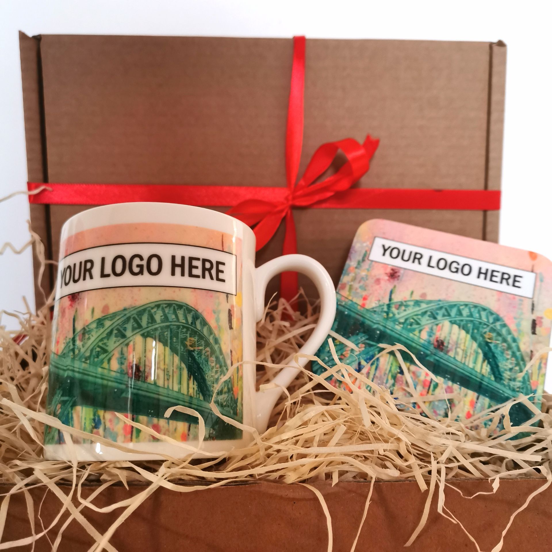 Gift box with two logo mugs on straw, tied with a red ribbon.