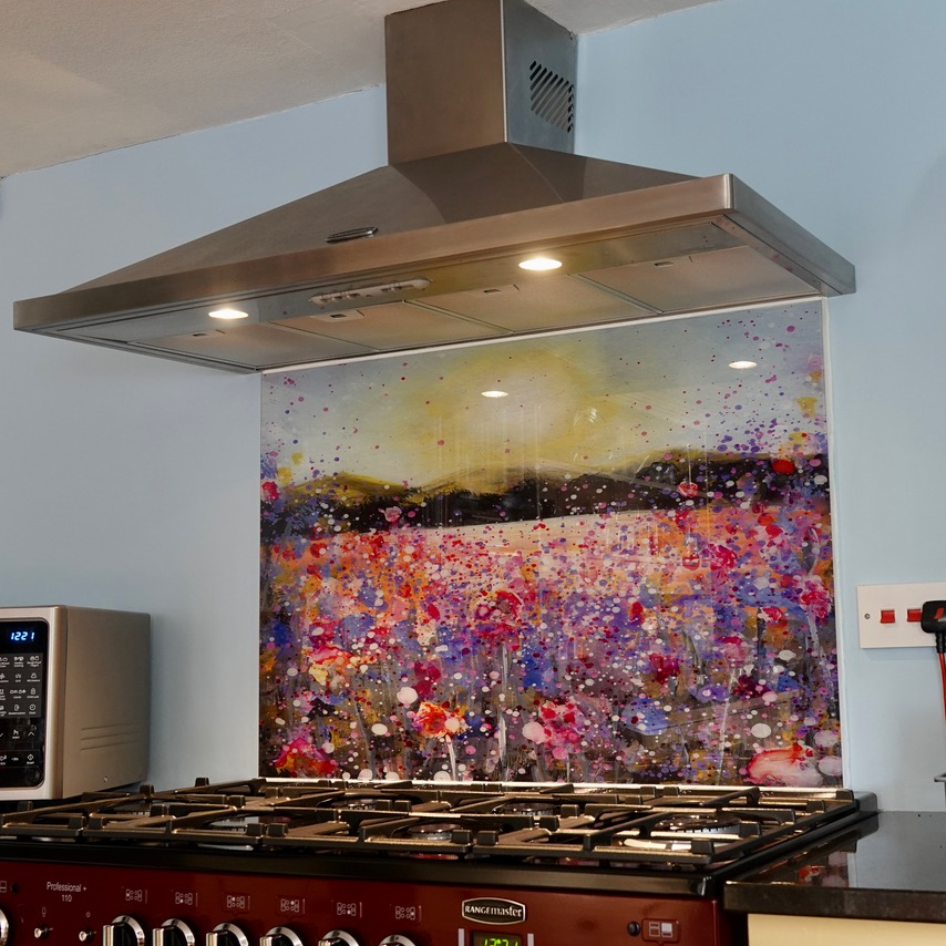 Modern kitchen with stainless range hood above a gas stove and a colorful abstract backsplash
