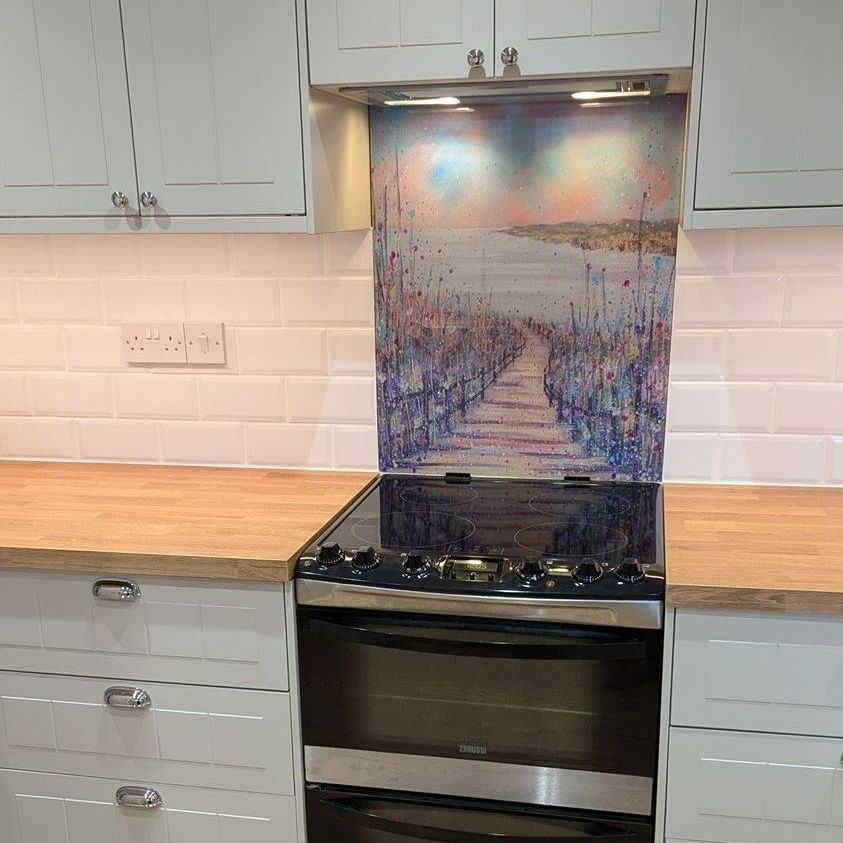 Modern kitchen with white cabinets, wood countertops, black stove, and a colorful backsplash panel