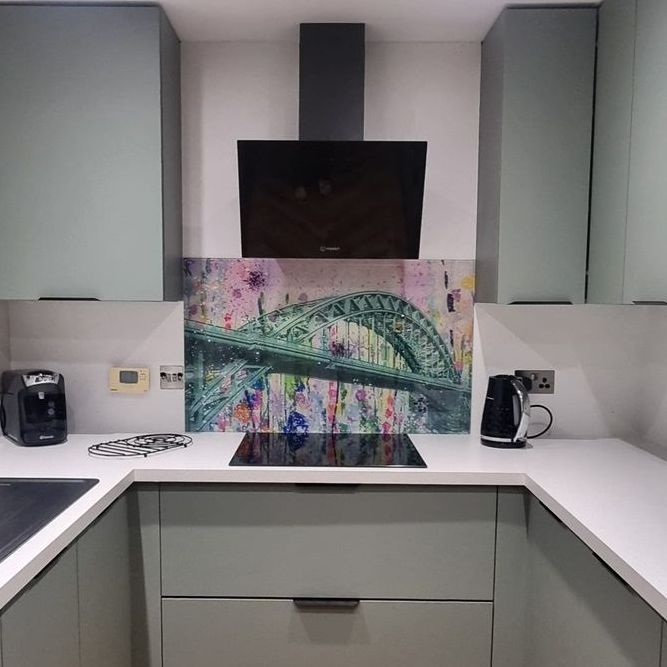 Modern white kitchen with black appliances and a colorful bridge painting on the counter