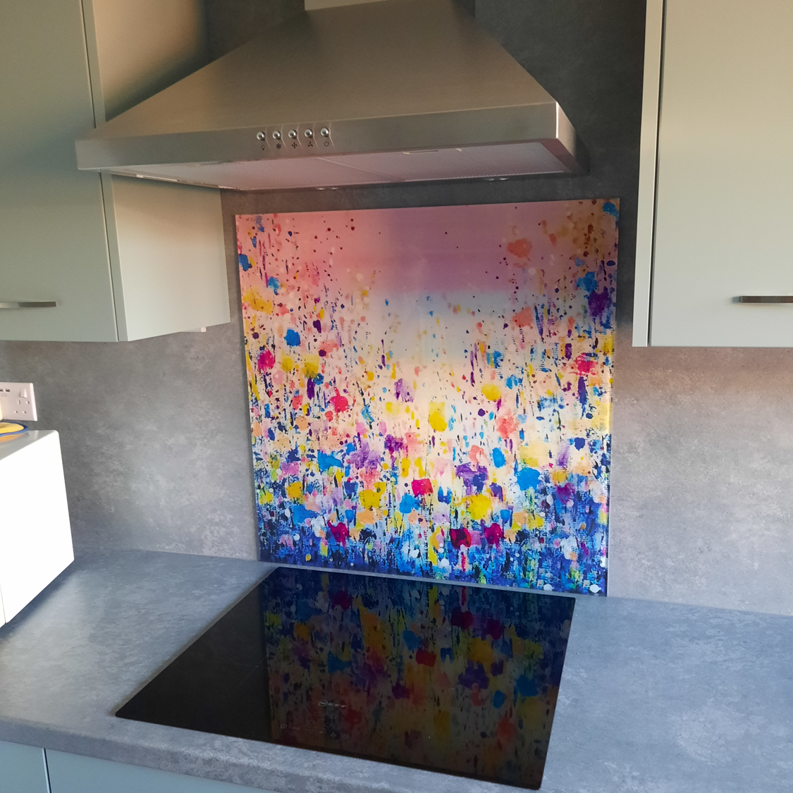 Modern kitchen with a colorful abstract backsplash above a black sink and gray countertops