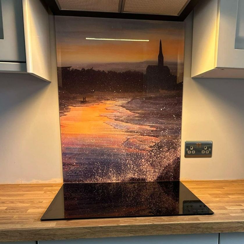 Sunset river mural backsplash behind a kitchen countertop with wood surface and black glass cooktop