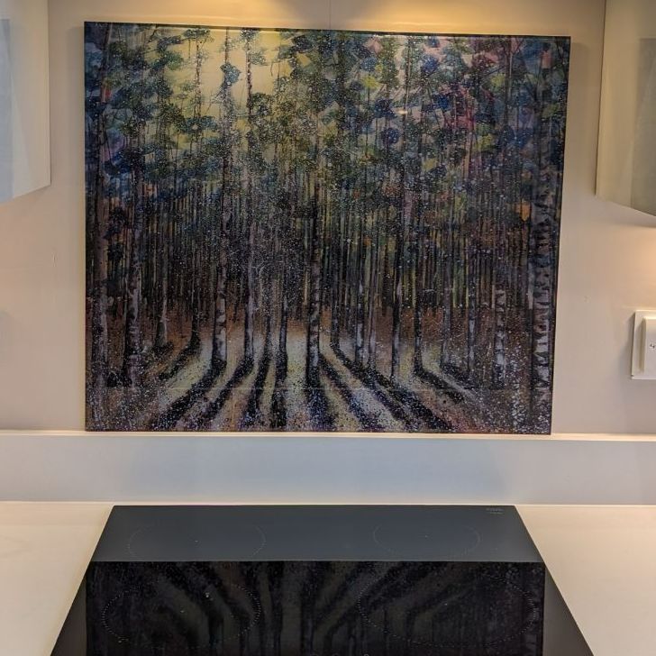 Abstract forest painting with tall tree trunks in muted blue, green, and purple tones above a dark console table.