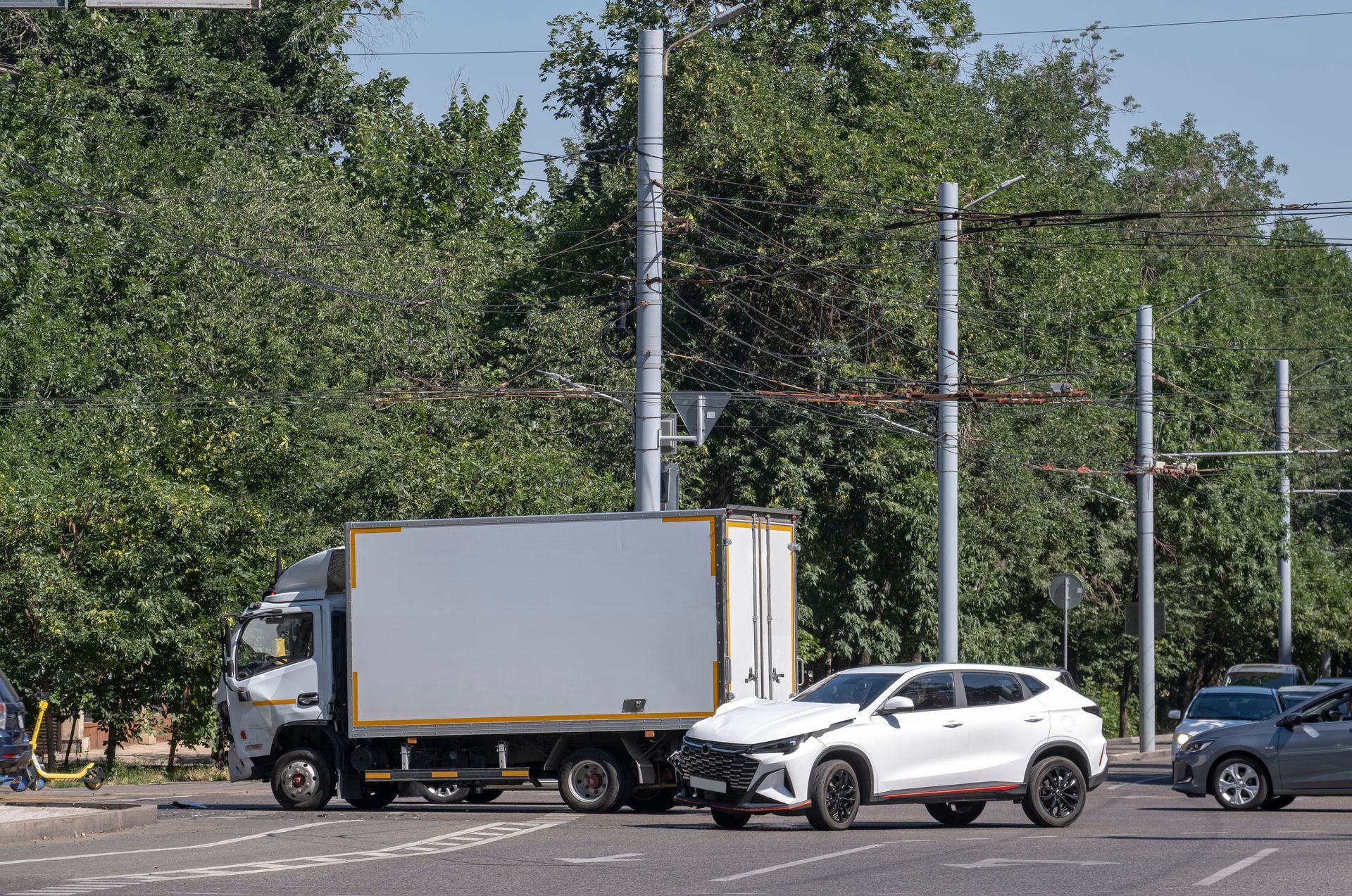A white commercial box truck stopped behind a car after a minor collision at a city intersection A white commercial box truck stopped behind a car after a minor collision at a city intersection