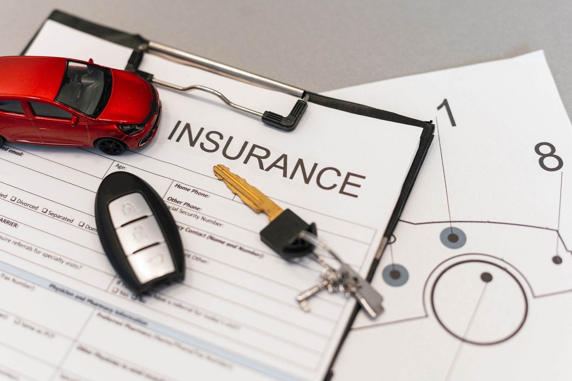 Top view of car insurance claim form with car key and car toy on desk.