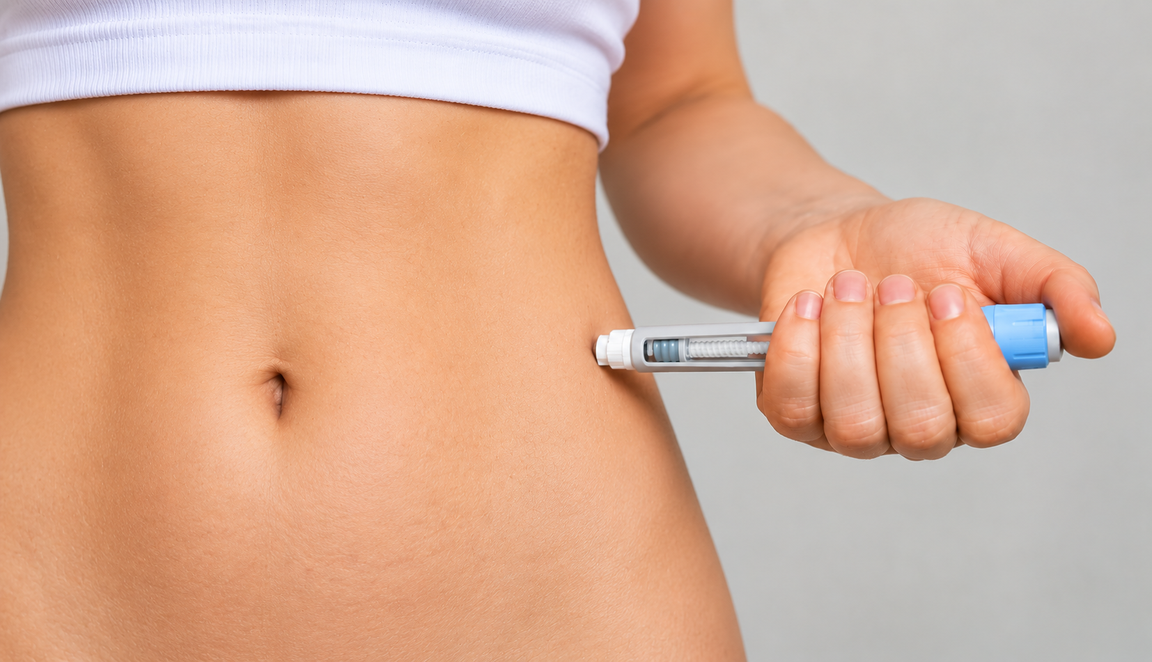 Person holding a syringe against their belly, suggesting a weight-loss injection.