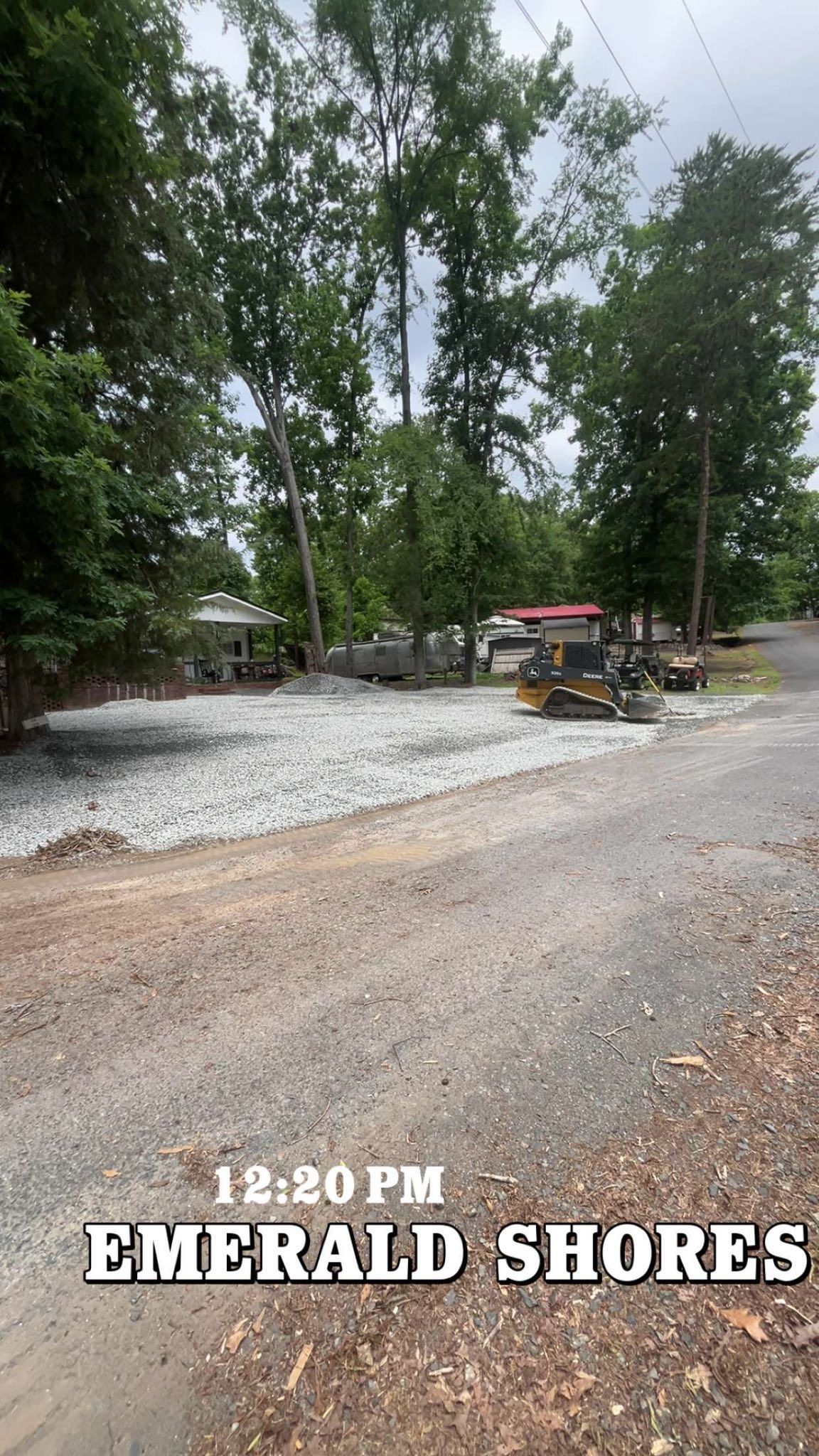 Gravel lot with trees and a small red-roofed cart; text reads “12:20 PM EMERALD SHORES.”