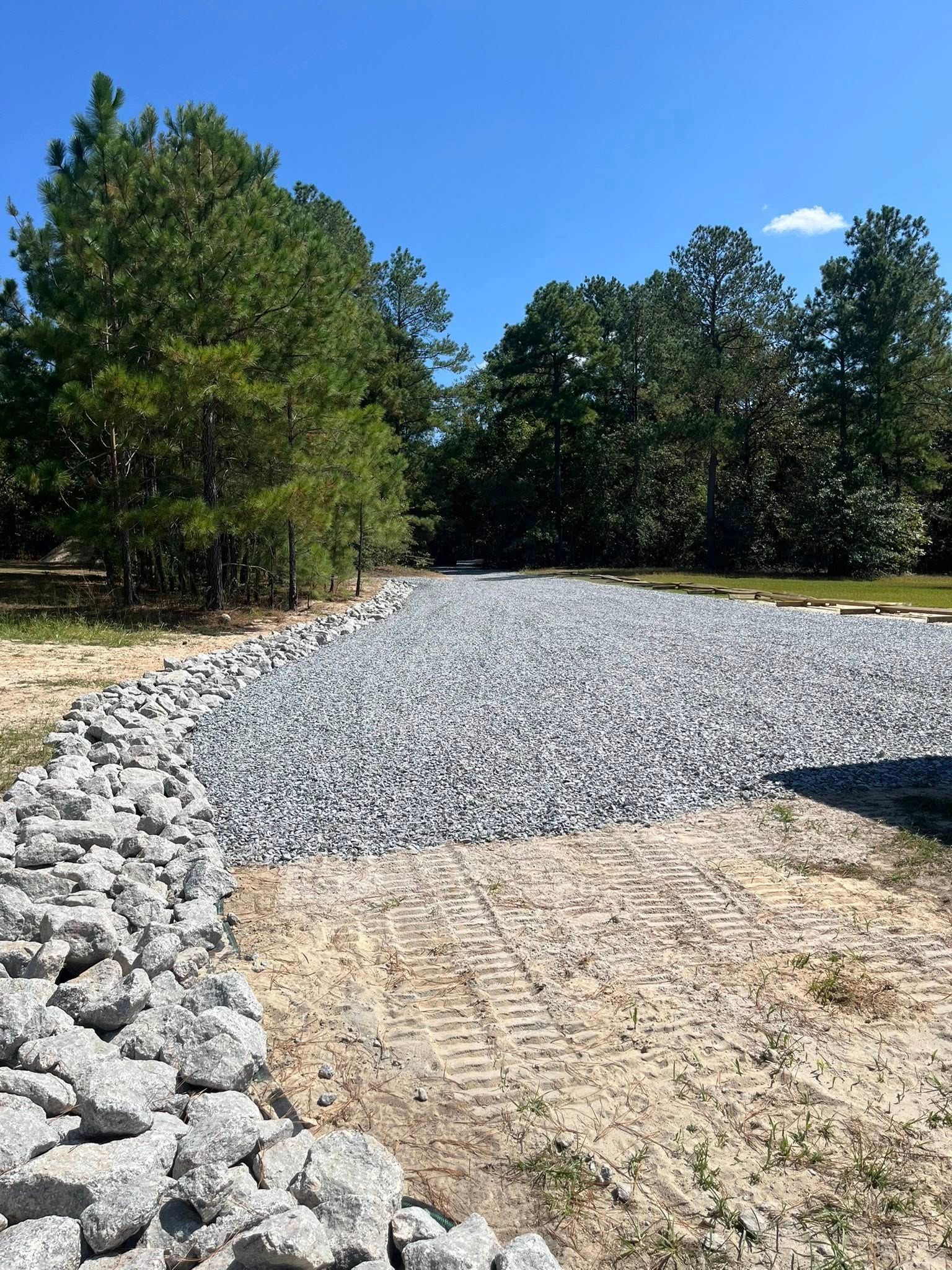Gravel path curving through a wooded area under a clear blue sky