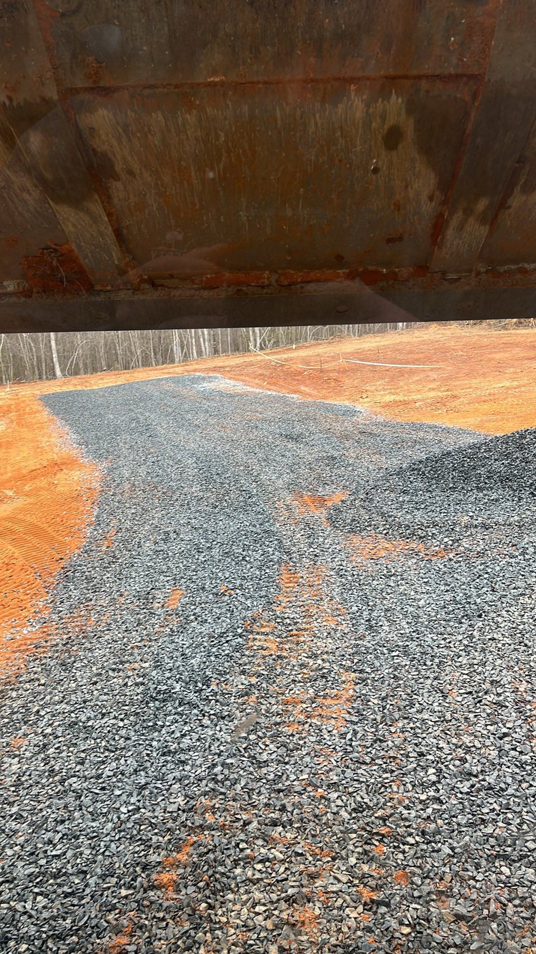Rusty metal wall above orange and blue gravel ground