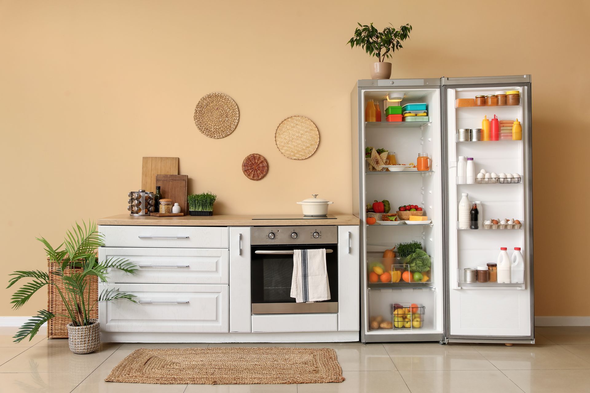 Modern kitchen with open fridge, white cabinets, and potted plants on a beige floor