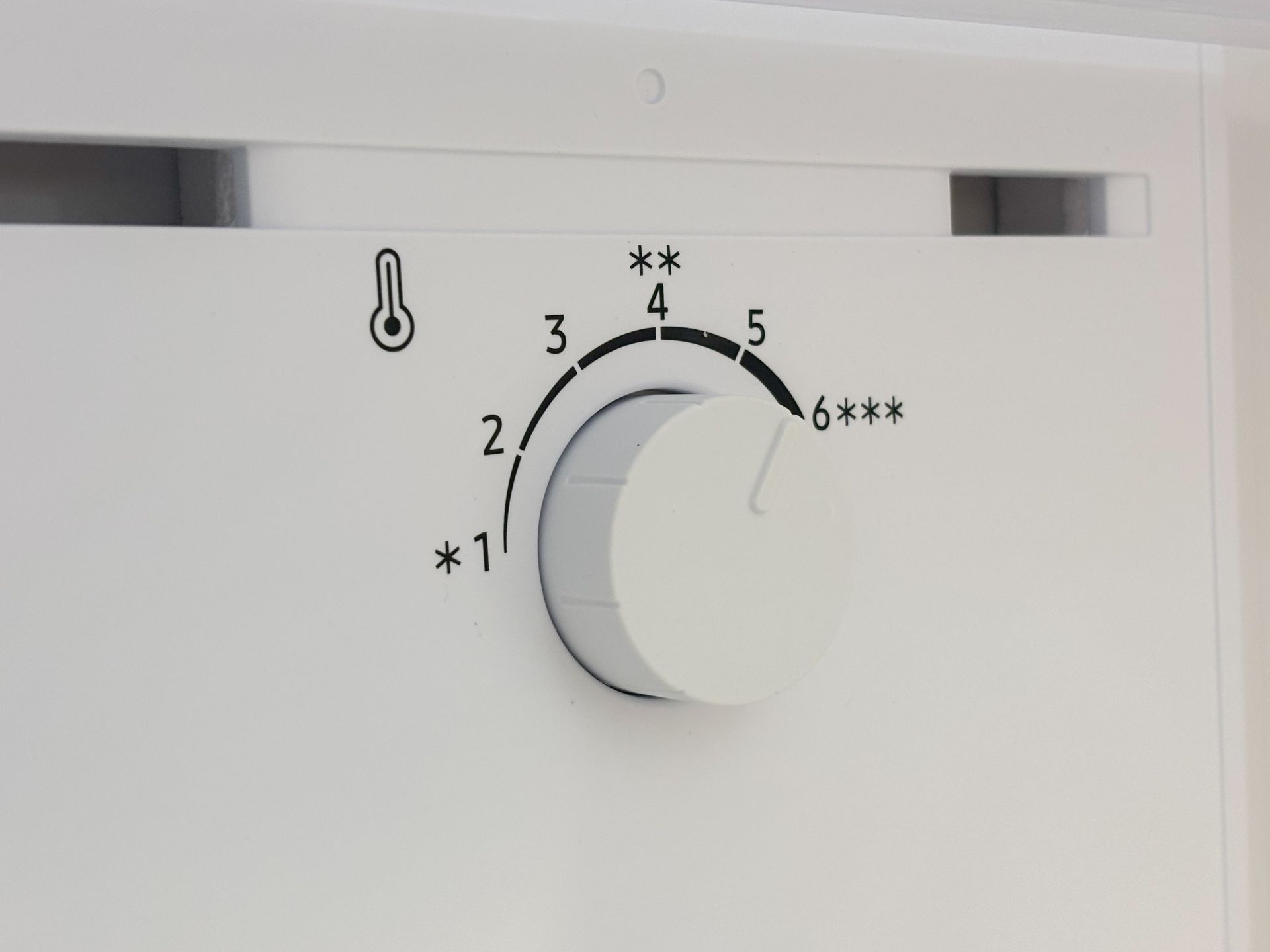 Close-up of a white thermostat dial with temperature settings 1 to 6 and snowflake symbols.