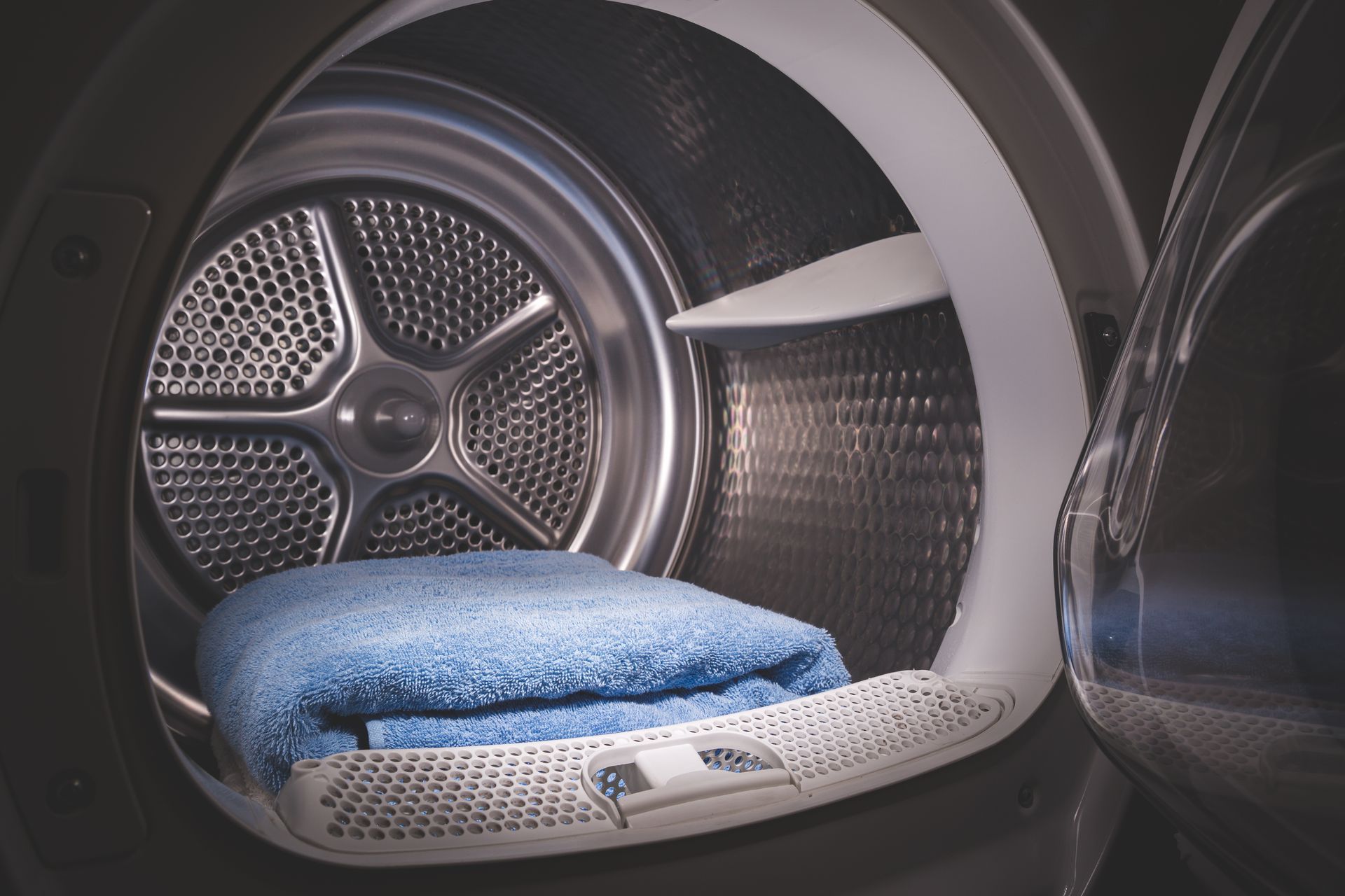 Blue blanket inside a front-loading dryer with the drum door open