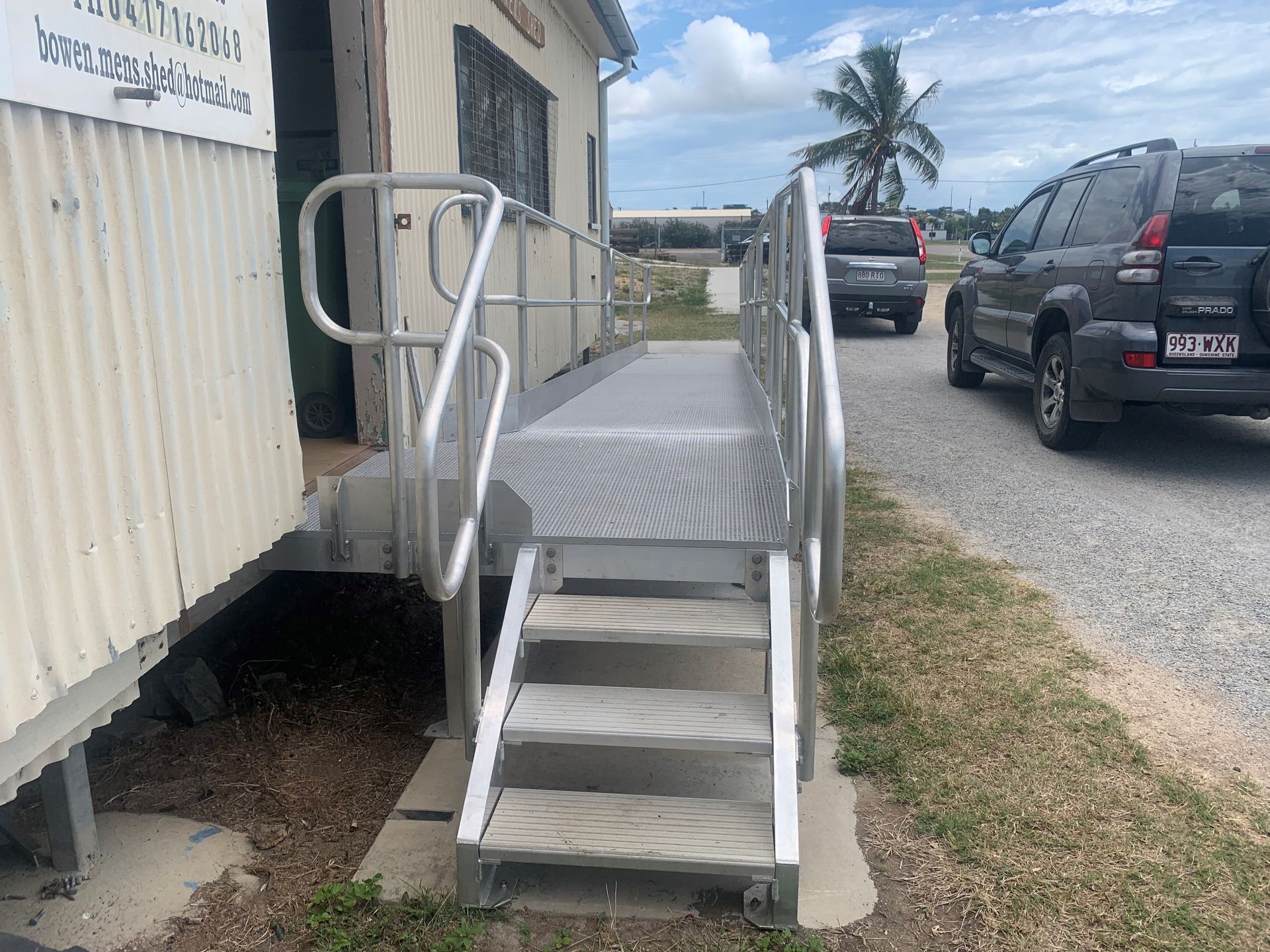 Temporary Wheelchair Ramp Beside a Beige Building, With Cars on a Gravel Road — Kaplan Engineering Pty Ltd In Bowen, QLD