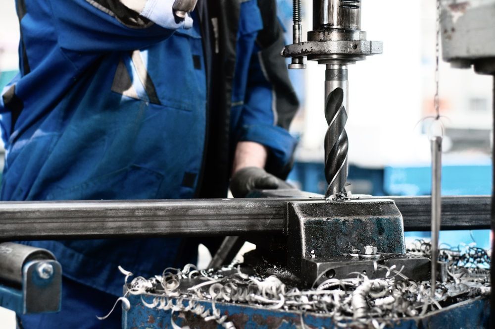 A Man Is Working On A Machine In A Factory — Kaplan Engineering Pty Ltd In Bowen, QLD