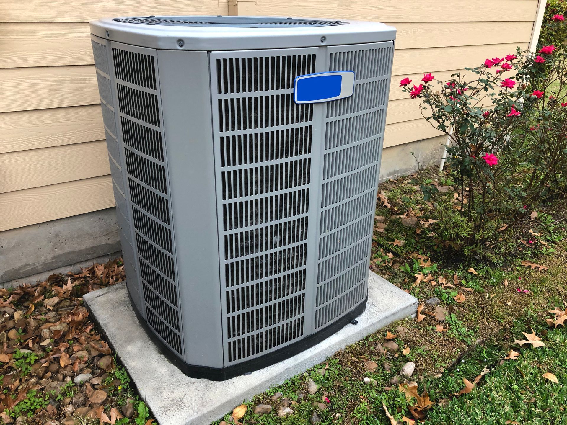 A large air conditioner is sitting on a concrete platform in front of a house.
