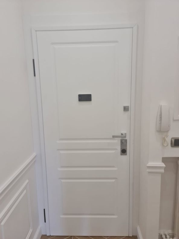 Porta interna bianca con un piccolo oggetto rettangolare scuro al centro della porta.