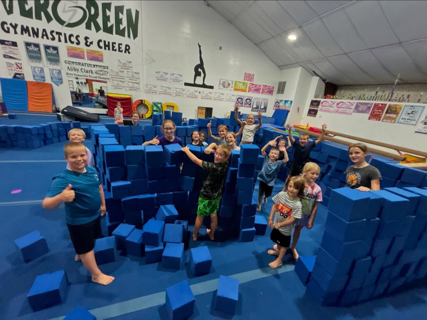 Children in a gymnastics gym playing in a large blue foam block pit