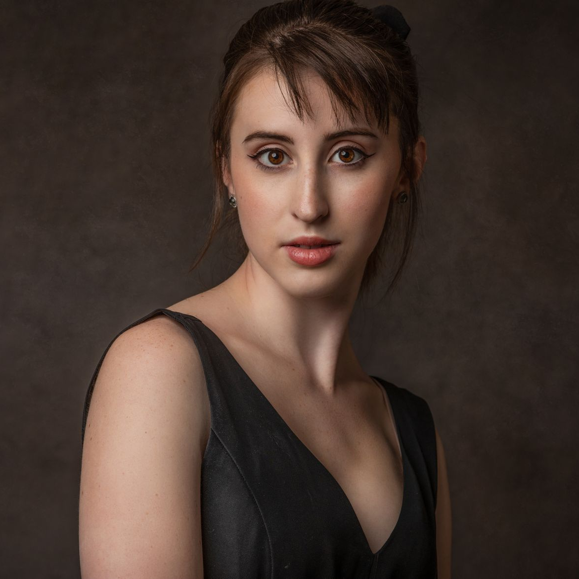 Portrait of a woman in a black dress against a dark studio background