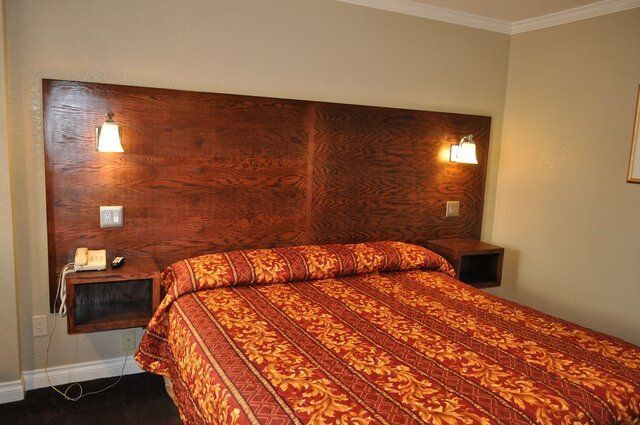 Hotel bedroom with a bed, headboard with lights, and nightstands.