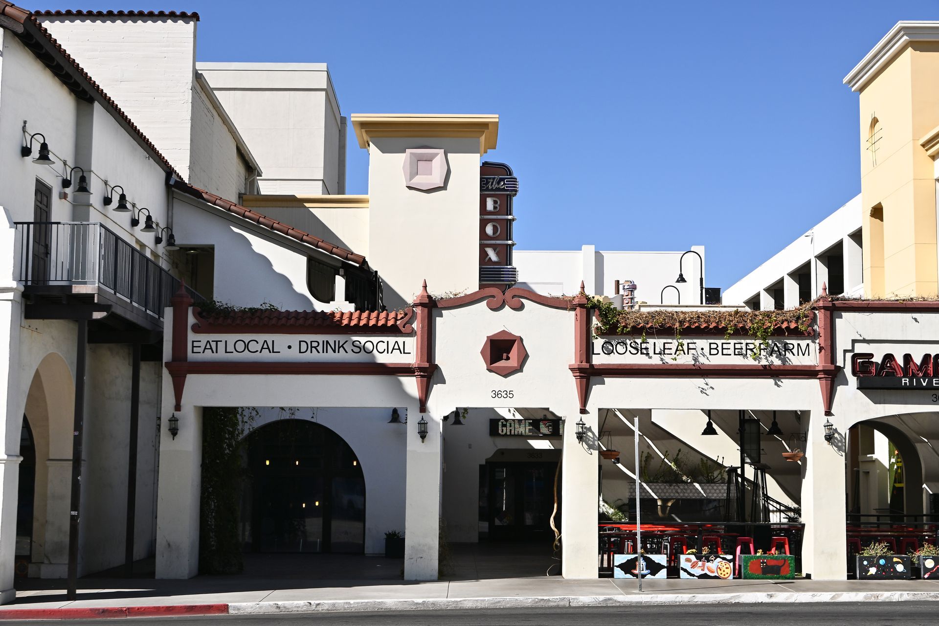Spanish mission-style building with arched doorways. Cream walls, red trim, and blue sky.