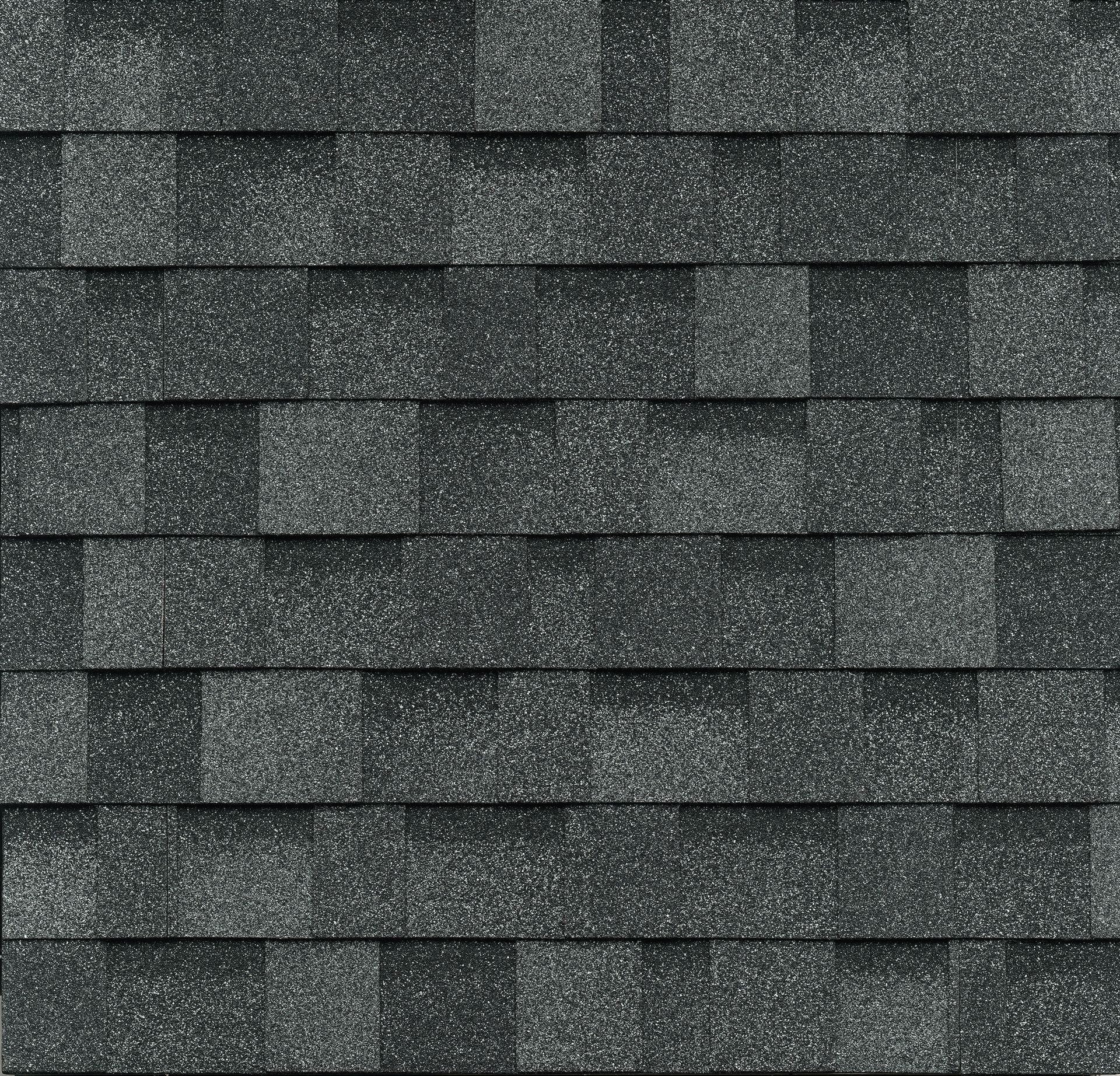 A repeating texture of charcoal grey architectural asphalt roofing shingles.