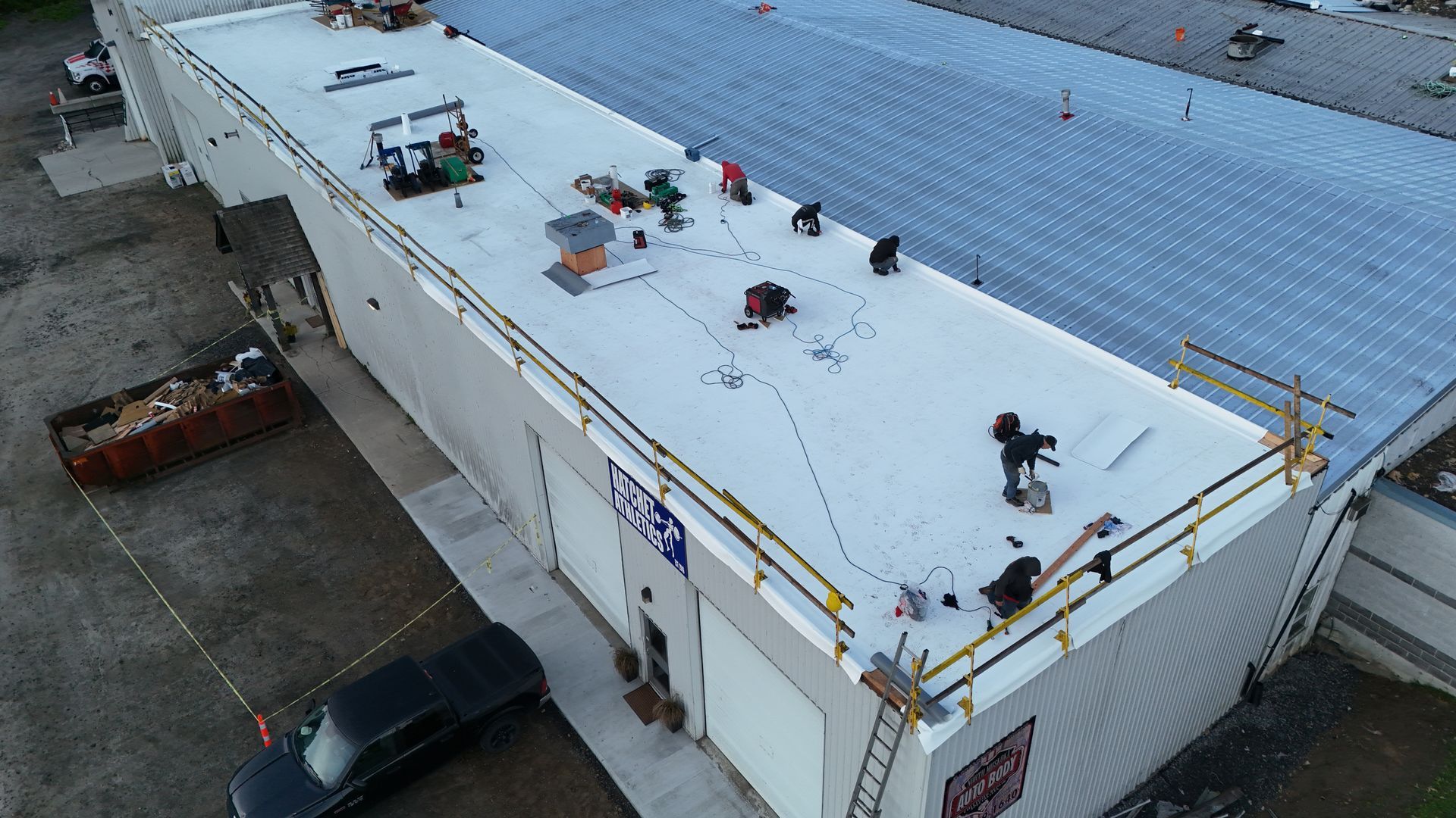 Workers on a flat roof with safety rails and equipment, preparing to work.