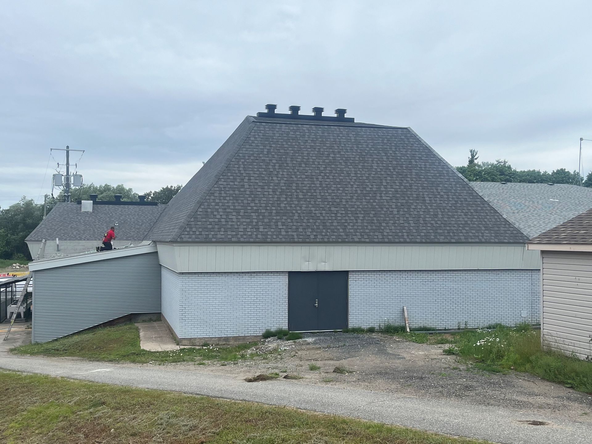Traditional white wooden building with a steep thatched roof and small roof vents under an overcast sky