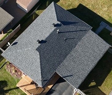 Aerial view of a gray shingled house roof with multiple gables and two vents.