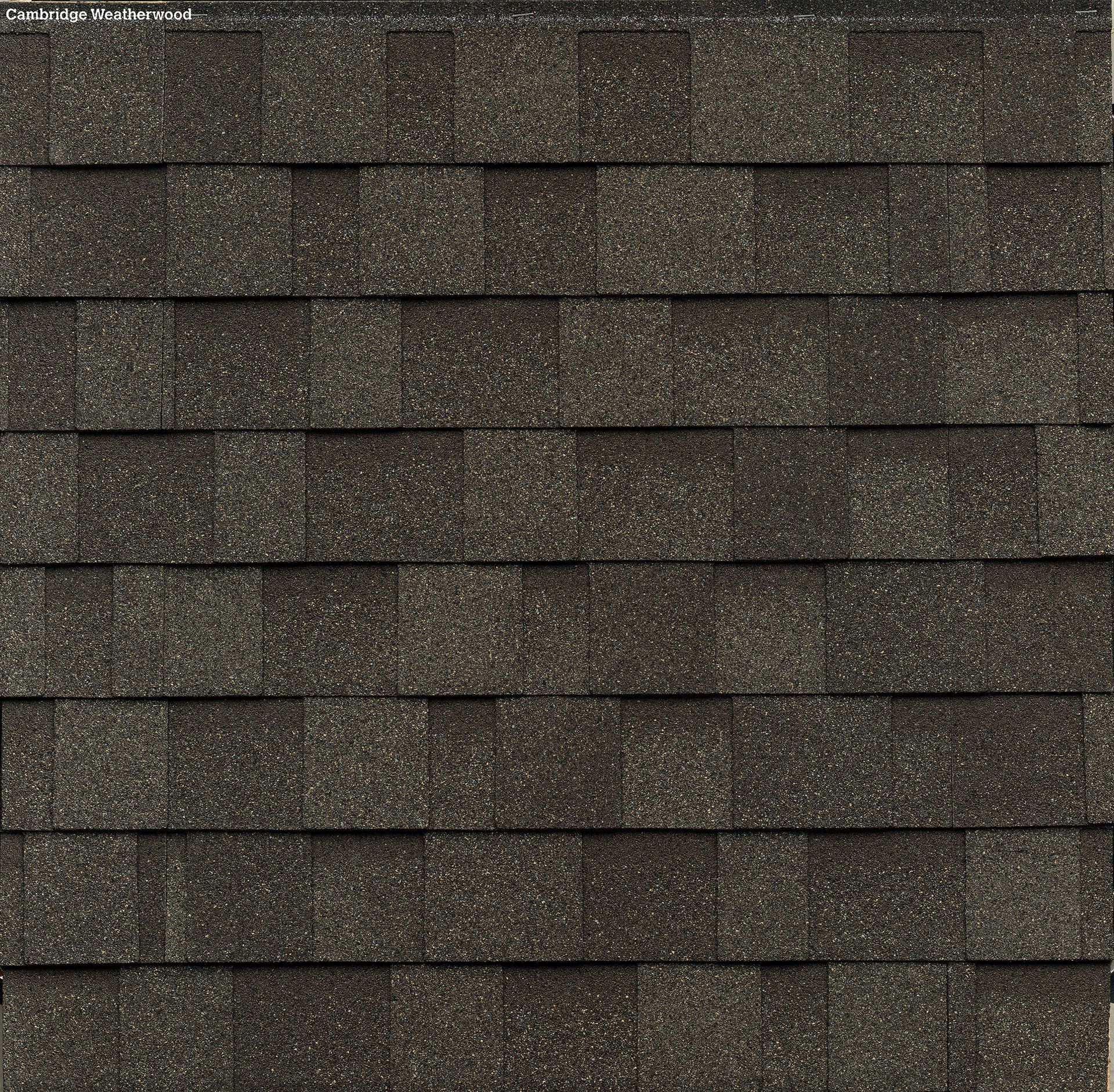 A close-up, top-down view of dark gray, rectangular asphalt roofing shingles arranged in an overlapping pattern.