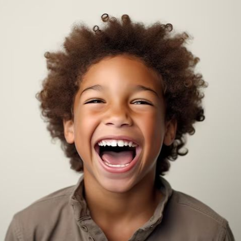 Boy with brown skin, laughing with mouth open, brown curly hair, neutral background.